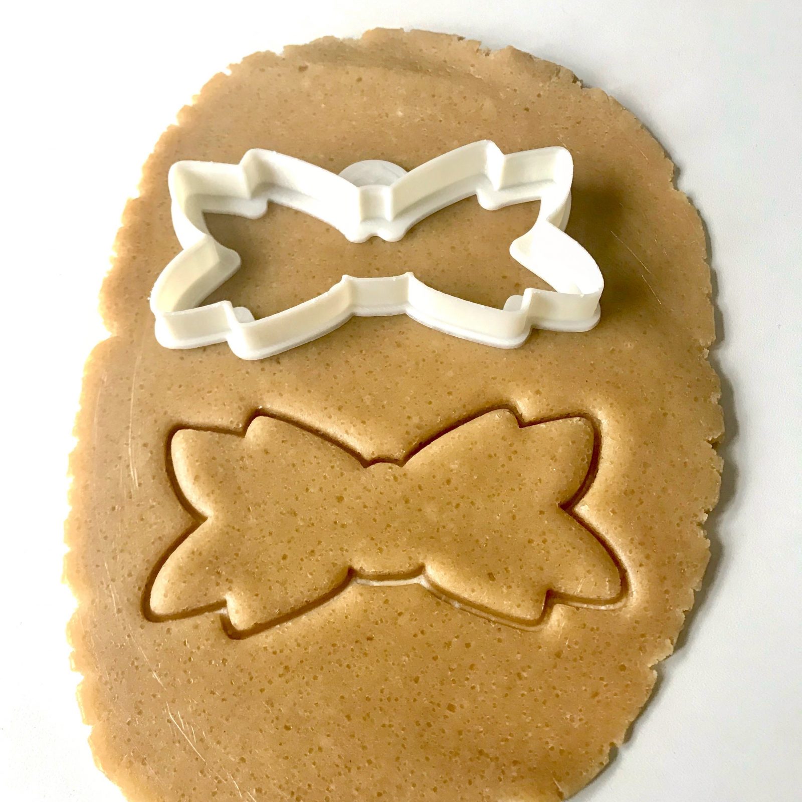 white bow outline cookie cutter on dough