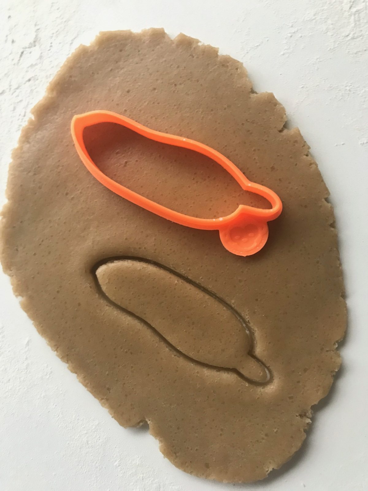 orange feather outline cookie cutter on dough
